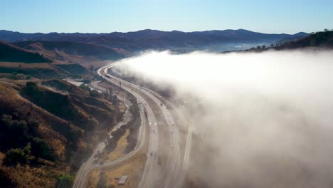 Antena-Sobre-Niebla-Y-Nubes-A-Lo-Largo-De-Una-Carretera-A-Través-De-Las-Estribaciones-De-California-Cerca-De-Ojai-California