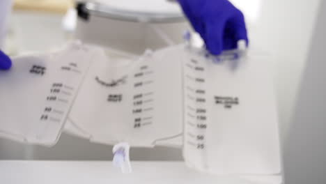 gloved hands demonstrate the plastic bag for blood and separated plasma. close up. centrifuge machine is getting ready for work.