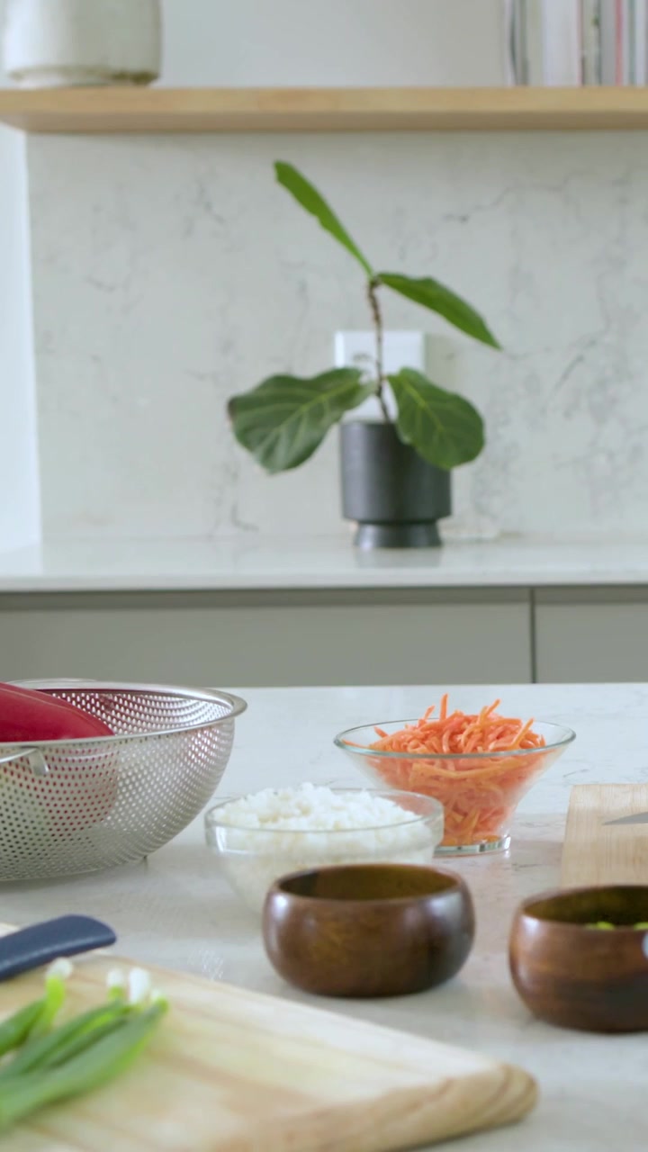 Video verticale: La telecamera si allontana mostrando il bancone della cucina con uno scolapasta e riso per la preparazione dei pasti.