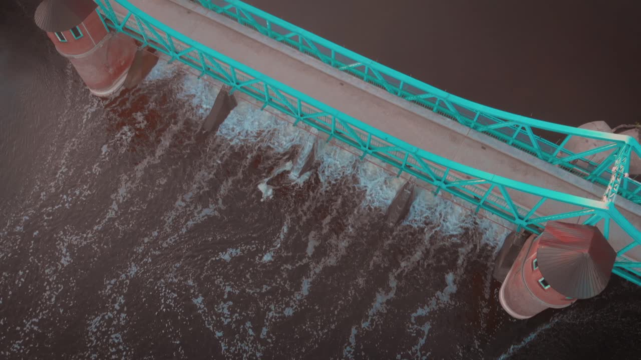 dron shot slowly revealing a wier on the river in Poland with a metal and brick bridge at sunrise