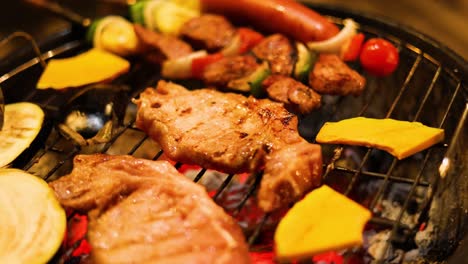 various meats and vegetables grilling over charcoal