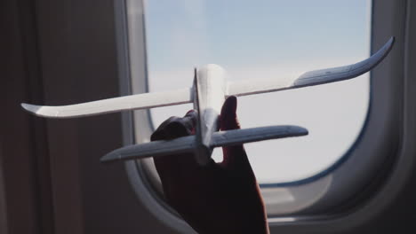 A-Child\'s-Hand-Holds-A-Toy-Avión-Against-The-Background-Of-The-Avión-Window-Dreams-And-Travel