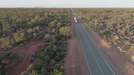 Drone-clip-showing-a-3-carriage-truck-driving-along-straight-road,-through-Australian-outback