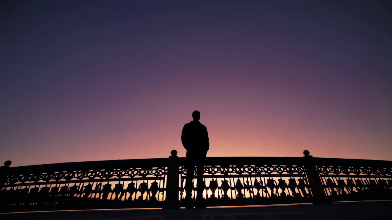 일몰 때 다리 위에 있는 사람의 실루엣