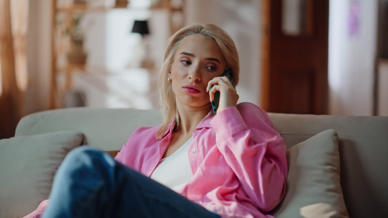 Upset woman talking mobile phone at sunny room closeup. Girl feeling headache