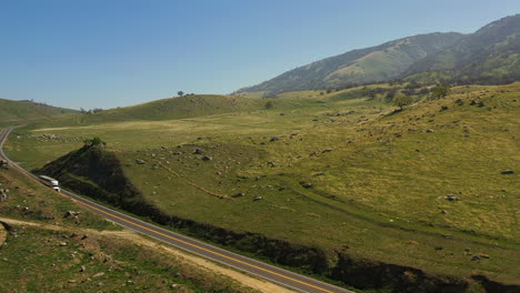en primavera, mientras la hierba es verde, un camión conduce a lo largo de una carretera en el sur de california - vista aérea
