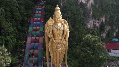 drone takes rotating hyperlapse of lord murugan statue in batu caves at kualar lumpur, malaysia which is located in the limestone hill