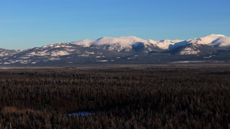 conifer forests and snow ridge near lake laberge in whitehorse, yukon, canada. aerial drone shot