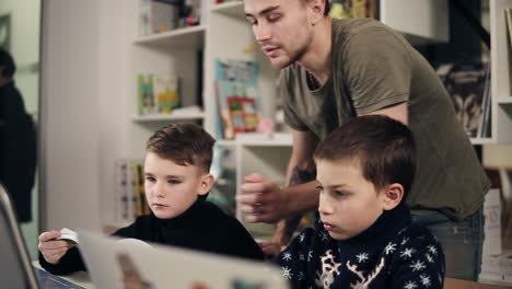 Footage-of-two-boys-and-their-young-male-programmer-teacher-in-a-classroom-learning-how-to-use-laptop.-Alternative-education-for-children.