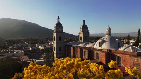 Rückwärtsaufnahme-Aus-Der-Luft-Des-Antiken-San-Bautista-Tempels-Während-Der-Herbstsaison-Bei-Sonnenuntergang---Stadtbild-Von-Tuxpan-Im-Hintergrund,-Mexiko