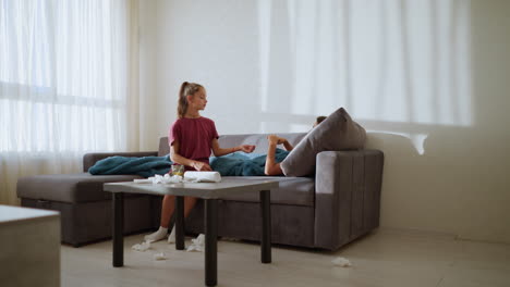 caring sister hands thermometer to sick brother with high fever, tissue litter scattered around as he checks his temperature, showing concern and care in a cozy home setting