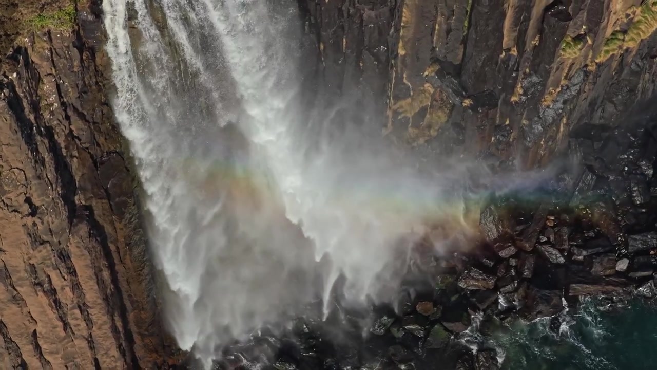 Le maestose cascate di Mealt scendono a cascata dalle aspre scogliere di Kilt Rock sull'isola di Skye, con un bellissimo arcobaleno che si forma nella nebbia.