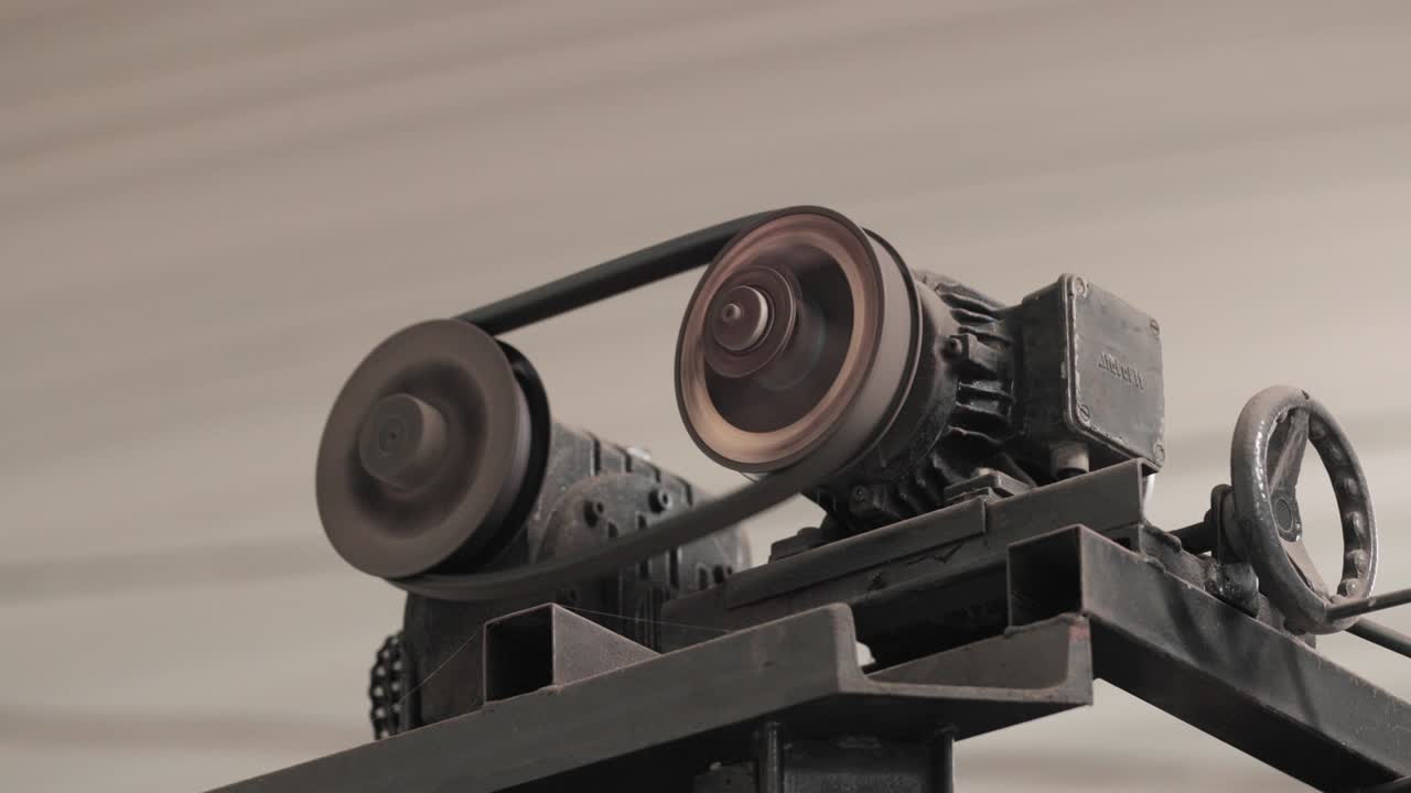 engranajes metálicos de una máquina industrial que giran con una correa serpentina