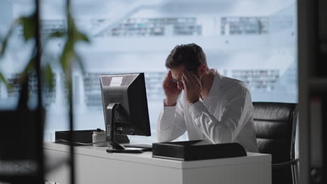 man sit indoor closed eyes rub temples suffering from headache. stressed young man in glasses suffering from muscles tension having painful head feelings due to computer overwork or sedentary working