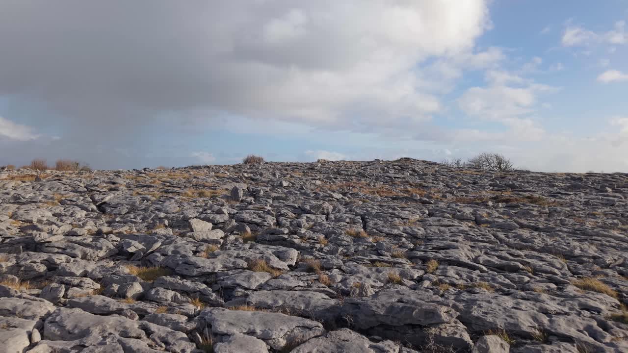 The Burren, County Clare, Ireland - The Rugged Limestone Terrain Features Characteristic Cracks, Sparse Vegetation, and a Partly Cloudy Sky Overhead - Drone Flying Forward