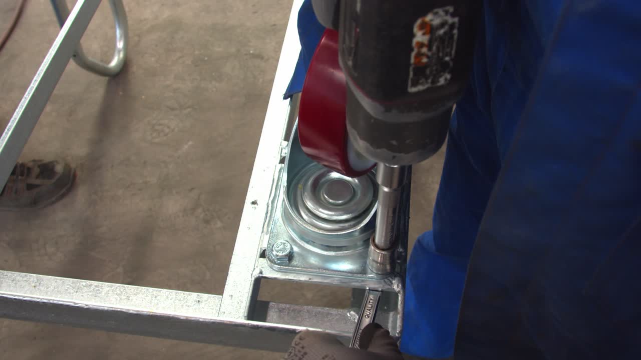 Worker tighten screw using electric tool inside workshop, handheld view
