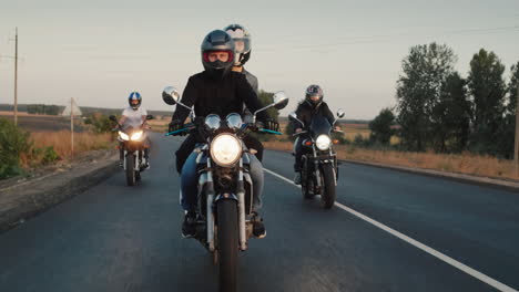 a group of bikers rides on the highway in the evening at sunset