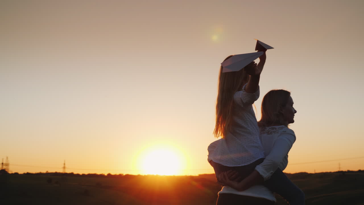 la niña está sentada sobre los hombros de su madre jugando con aviones de papel un video familiar feliz 4k