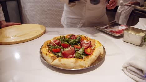 chef adds sauce on top of the baked pizza