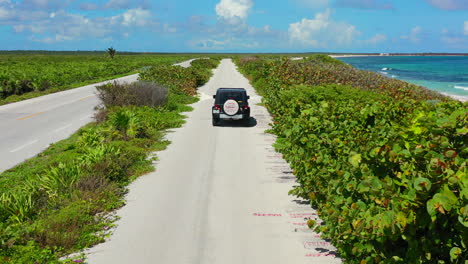 suv driving on tropical coastline road on sunny summer day in cozumel mexico