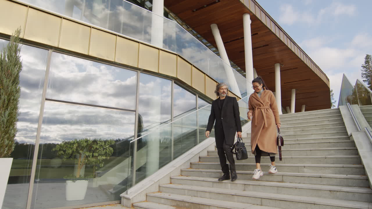 Stylish couple walking down modern building stairs