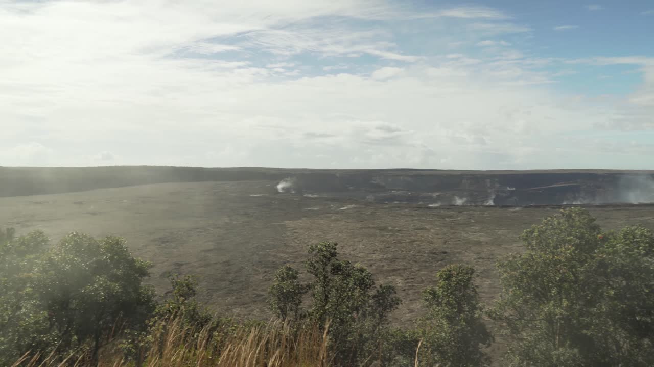 panorámica de derecha a izquierda del cráter del volcán con grandes cantidades de vapor y humo saliendo del suelo y cubriendo el bosque