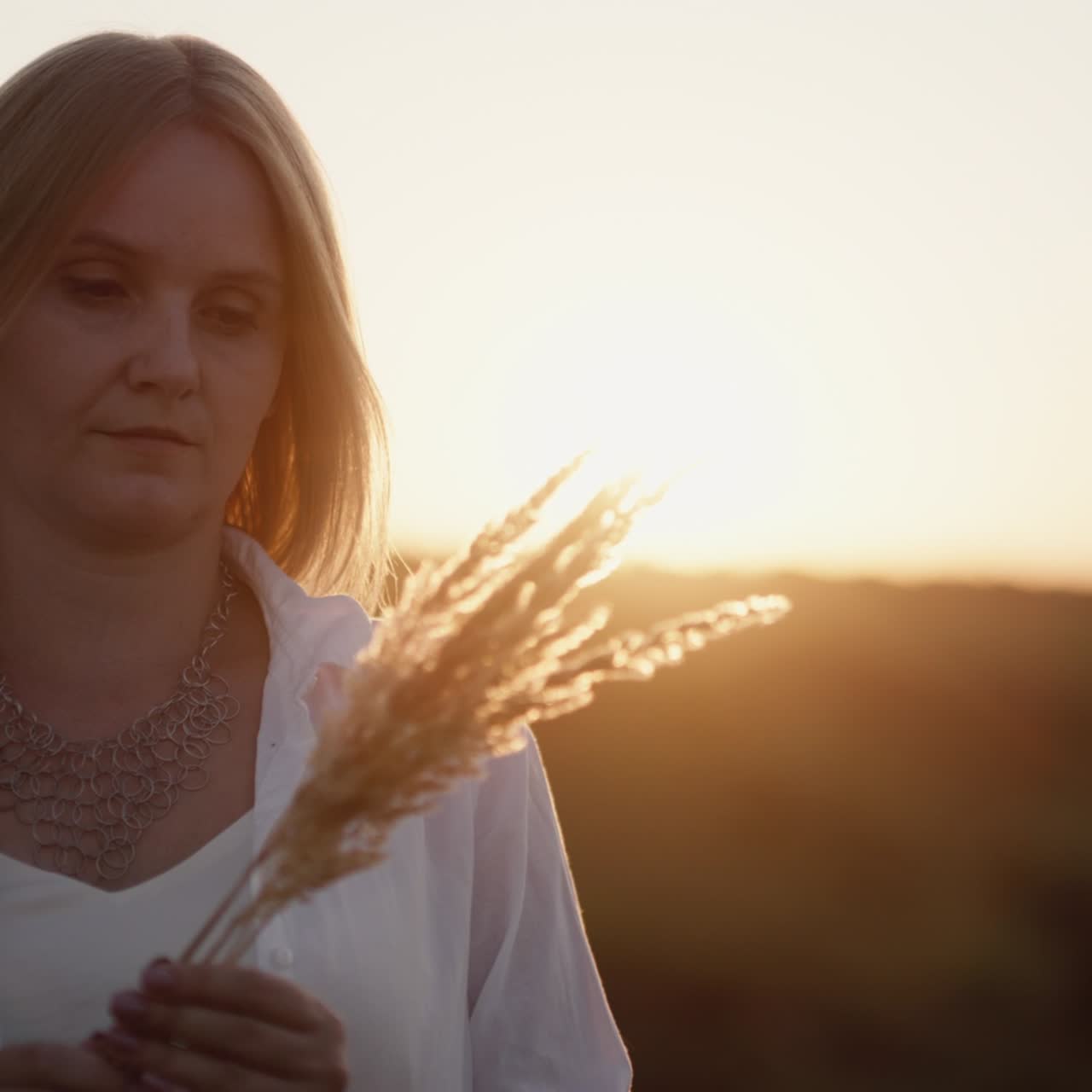 Woman stands at sunset in a field of grass 2