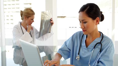 Surgeon-using-a-laptop-sitting-at-table