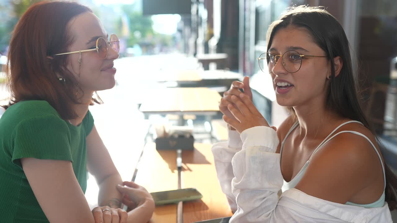 dos amigas hablando en un café al aire libre