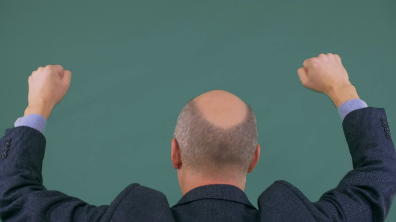 Bald businessman in suit protesting with fists up. Man rise hands up.