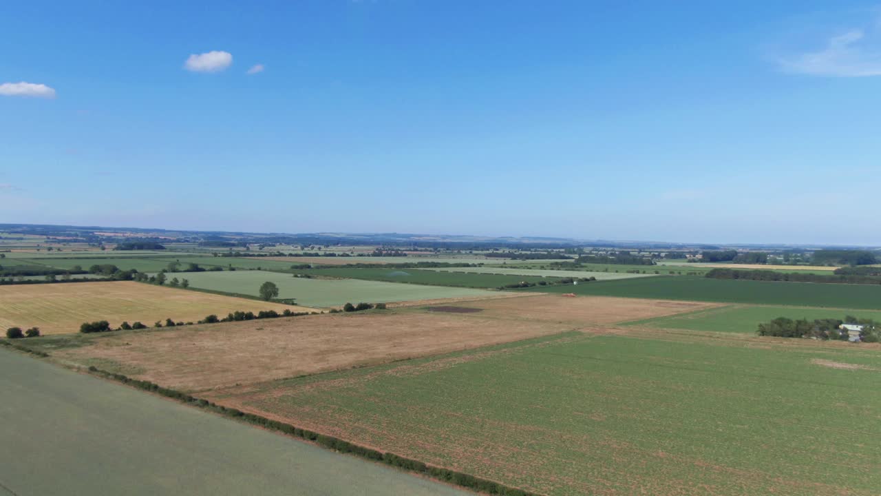 Drone fly over very flat farming fields in north of England of sunny clear blue sky day