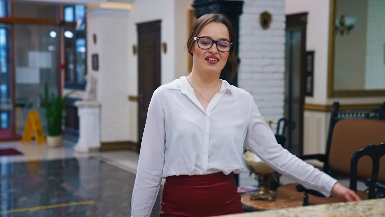 Charming lady with suitcase in the reception lobby. Girl approaching hotel reception to take the key. Portrait of gorgeous woman pressing bell button at reception desk.