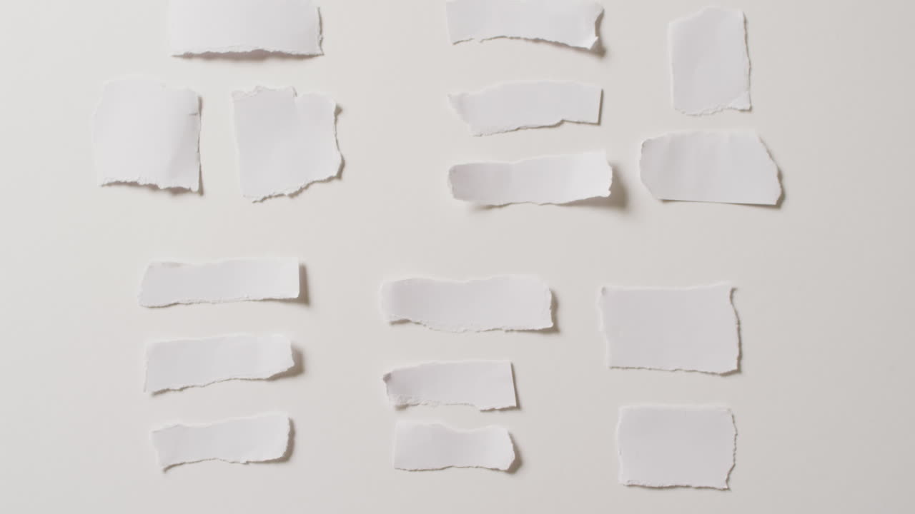video de un primer plano de varias piezas de papel rasgadas sobre un fondo blanco