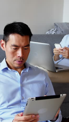 man using digital tablet while woman using mobile phone