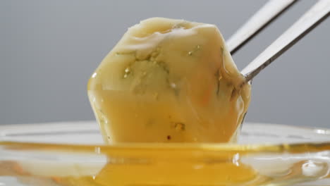 Tasty blue cheese with rosemary, honey and walnuts on white table, close up of Dorblu in cafe pouring in honey.