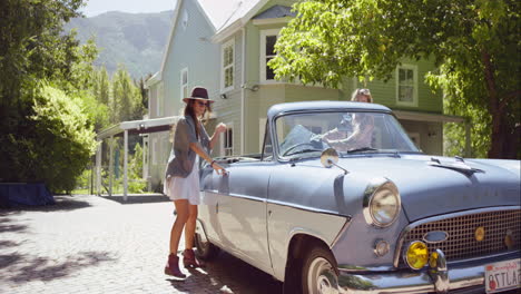 Dos-Hermosas-Amigas-Empacando-Un-Auto-Convertible-Antiguo-Y-Partiendo-Para-Un-Viaje-Por-Carretera