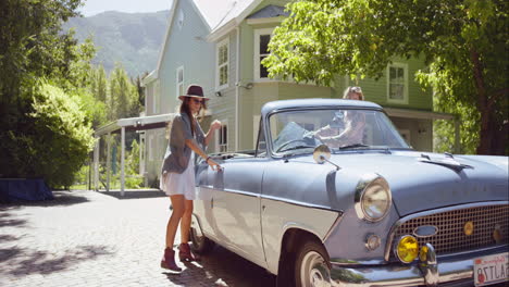 dos hermosas amigas empacando un coche descapotable de época y partiendo para un viaje por carretera