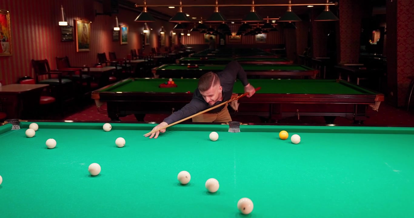 Man Taking a Shot During a Game of Billiards in a Pool Hall