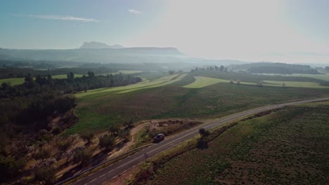 A-car-drives-along-a-scenic-countryside-road-under-a-clear-sky