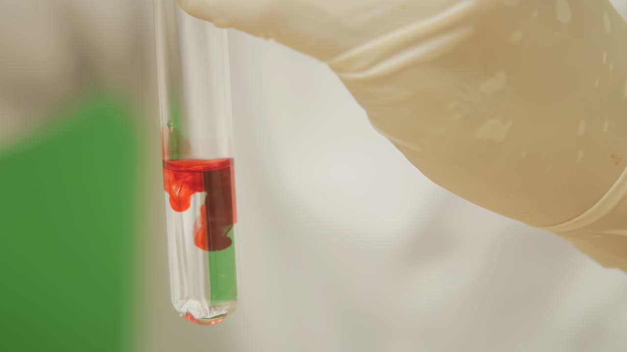 Scientist holding test tube with red and clear liquid in a laboratory