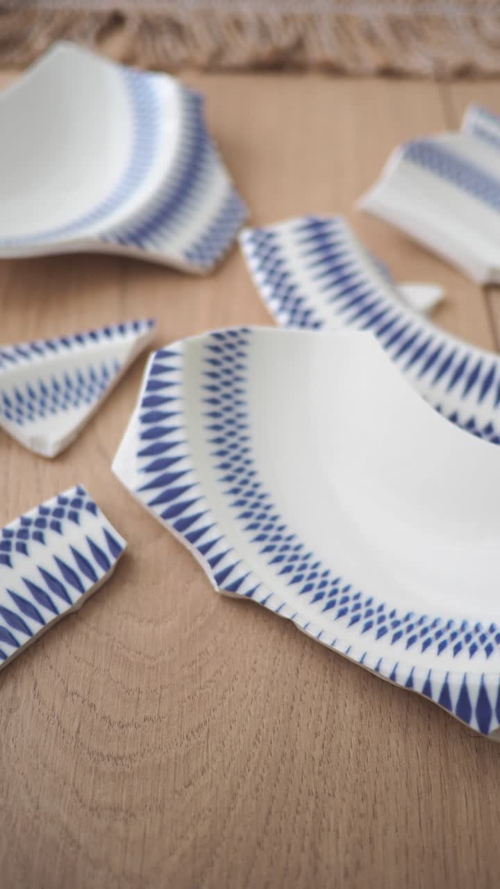 Piatto bianco rotto con motivo blu sparso su un pavimento di legno