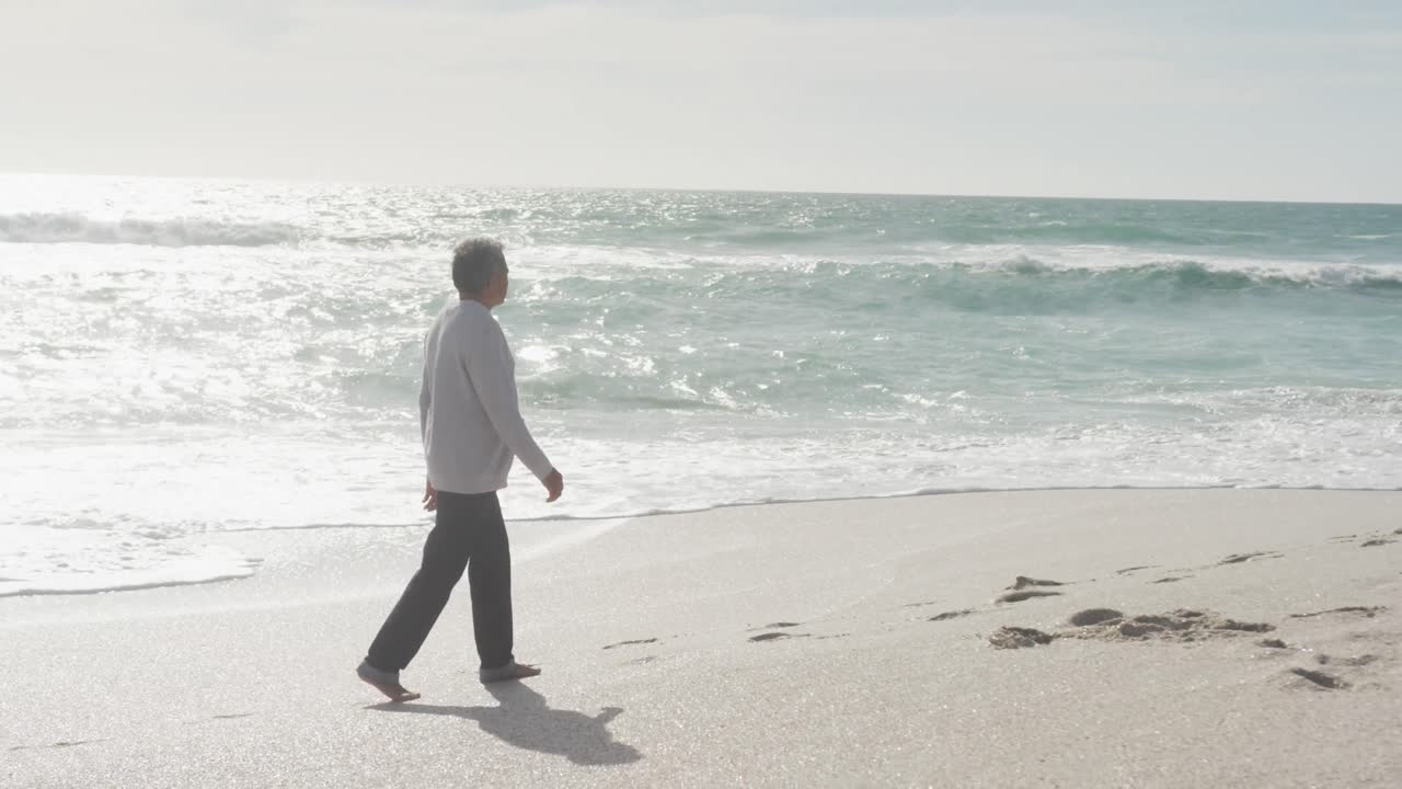 해가 지는 해변에서 걸어다니는 히스패닉 성인 남자의 측면 전망