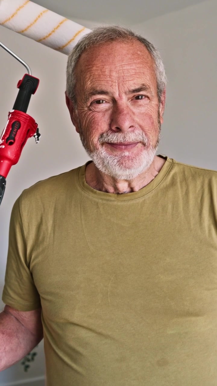 Senior Man Holding Paint Roller and Bucket in New Home