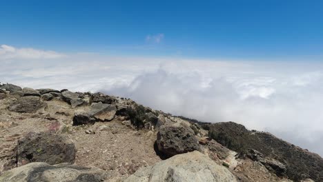 Mountain-peak-time-lapse-as-white-clouds-drift-through-blue-sky-below