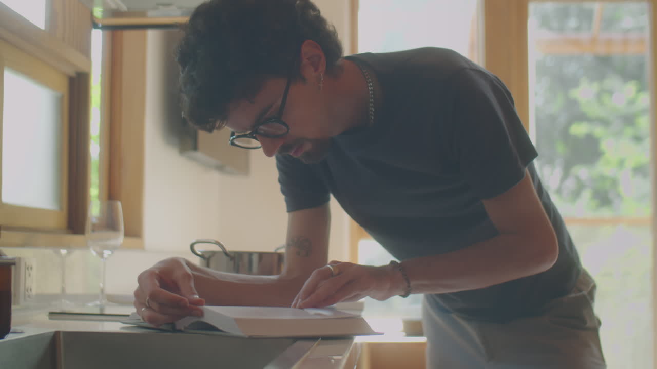 Man Reading Book while Cooking in Kitchen