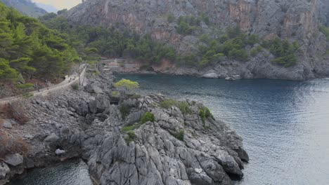 Spiralling-down-panoramic-drone-shot-of-Sa-Calobra-town-at-Mallorca,-Spain-during-a-sunny-day