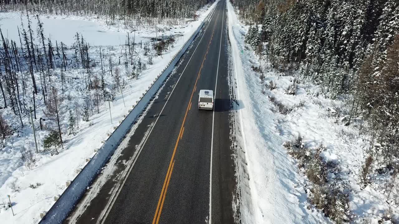 Furgone che attraversa una fredda e soleggiata giornata invernale con cielo azzurro nella campagna settentrionale del Canada - Ripresa aerea con drone 4K.