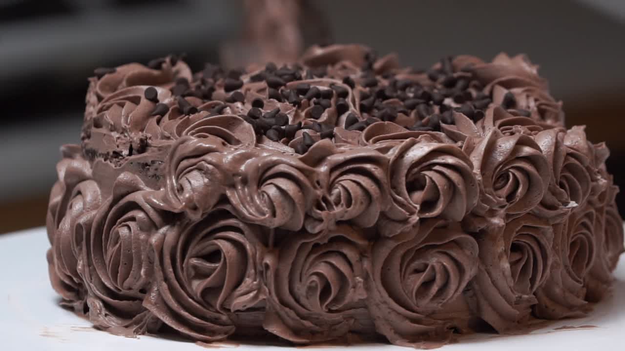 pastel de chocolate en la mesa giratoria con glaseado de diseño floral