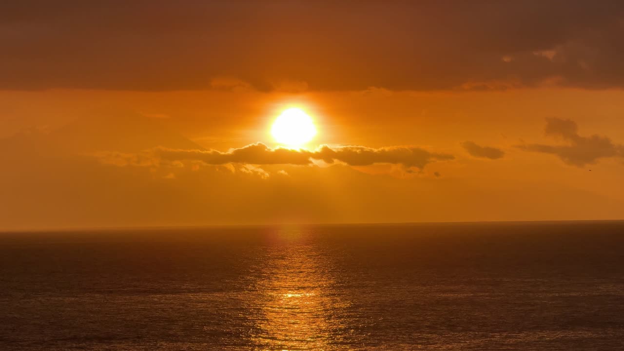 Dramatisk gylden solnedgang, der spejler sig i havoverfladen