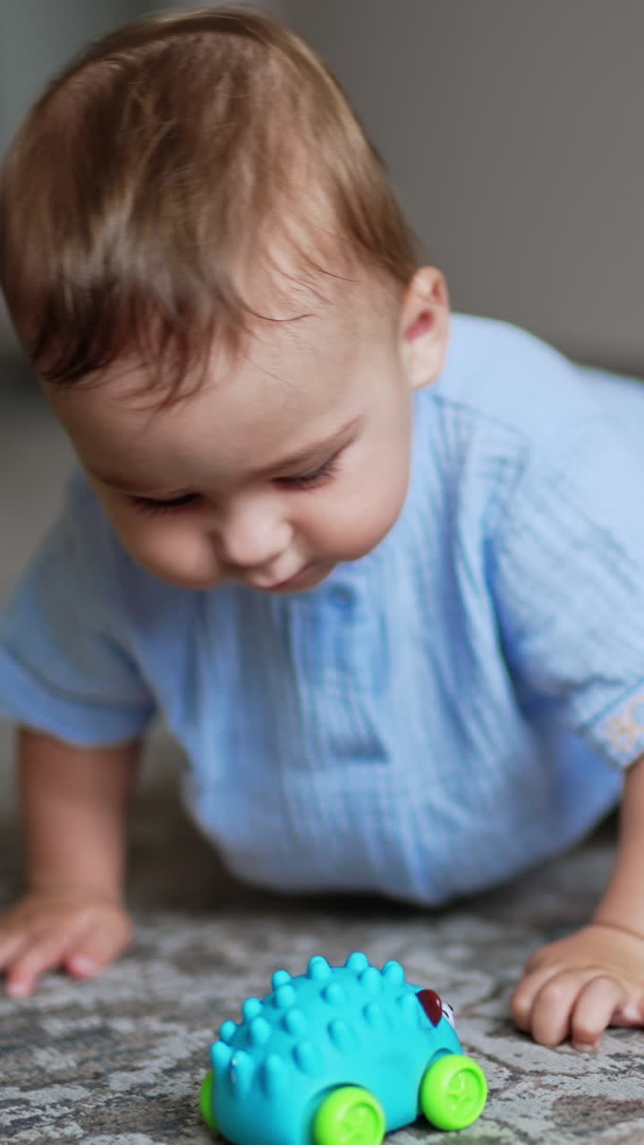 Healthy cute kid playing on the floor. Funny boy moves actively and smiling adorably. Close up. Blurred backdrop. Vertical video